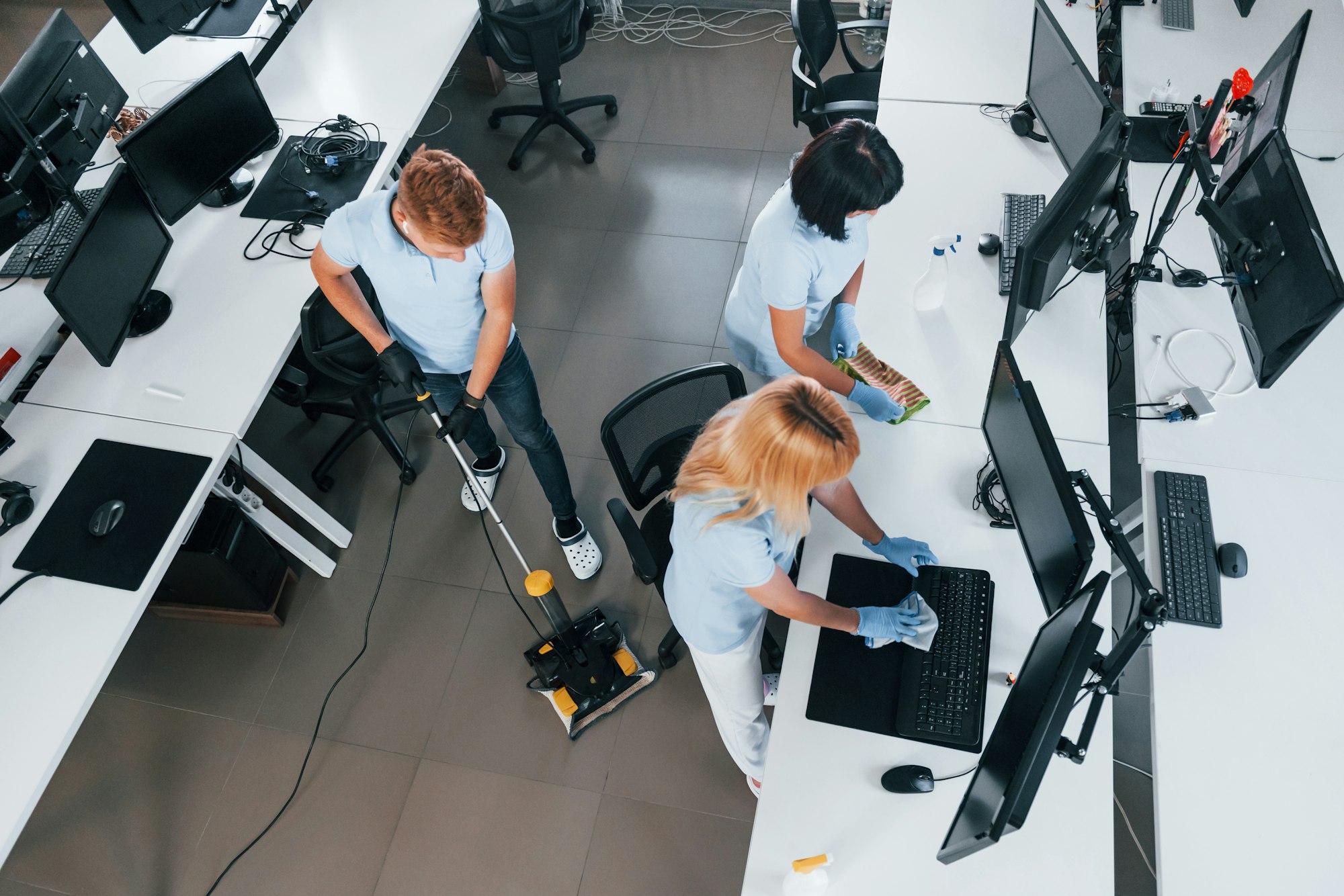 Top view. Group of workers clean modern office together at daytime