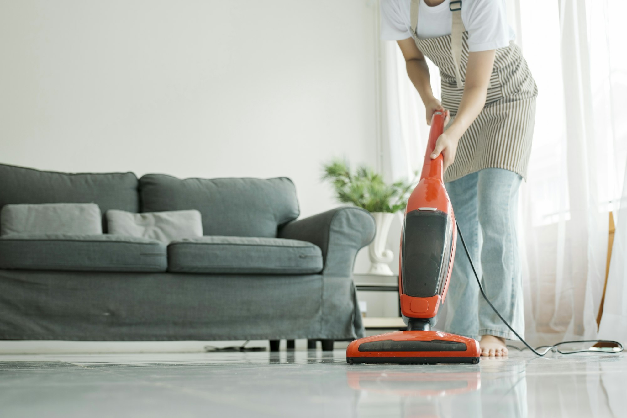 Young woman cleaning house with vacuum cleaner.